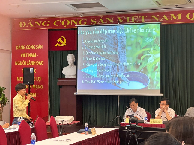 Một buổi hội thảo về chuỗi cung cao su tiểu điền tại TP Hồ Chí Minh, với một diễn giả đứng lên trình bày trước màn hình lớn chứa thông tin và nội dung liên quan đến yêu cầu đáp ứng EUDR, trong bối cảnh có bàn và ghế dành cho đại biểu tham dự.